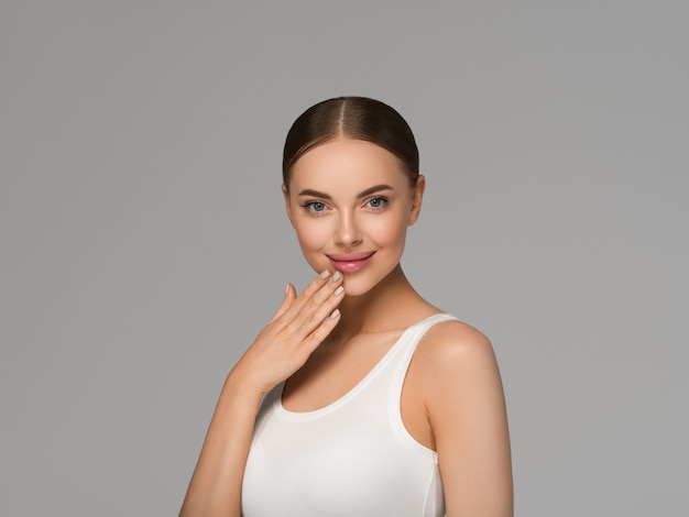 Mooie huid gezicht vrouw natuurlijke make-up gezonde huid aanraken van haar gezicht. Kleur achtergrond. Grijs