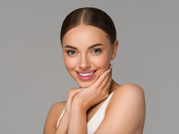 Mooie huid gezicht vrouw natuurlijke make-up gezonde huid aanraken van haar gezicht. Kleur achtergrond. Grijs