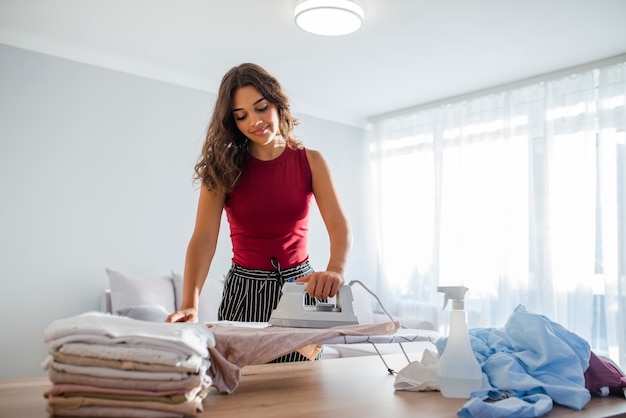 Mooie huisvrouw in goed humeur met ijzer en kleurrijke kleding