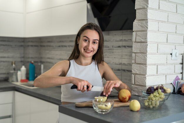 Mooie huisvrouw tijdens het kookproces op het ontbijt in de keuken. Vers fruit als gezondheidsvoedsel