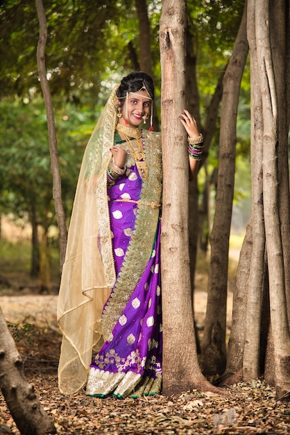 Foto mooie indiase bruid in traditionele saree die buiten in het park poseert