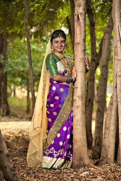 Foto mooie indiase bruid in traditionele saree die buiten in het park poseert