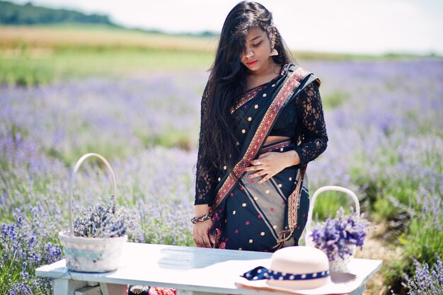 Mooie Indiase meid draagt traditionele saree indiase kleding in paars lavendelveld