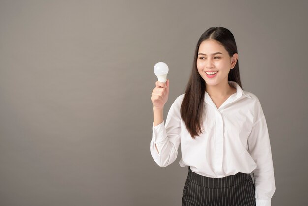 Mooie intelligente vrouw houdt gloeilamp in studio