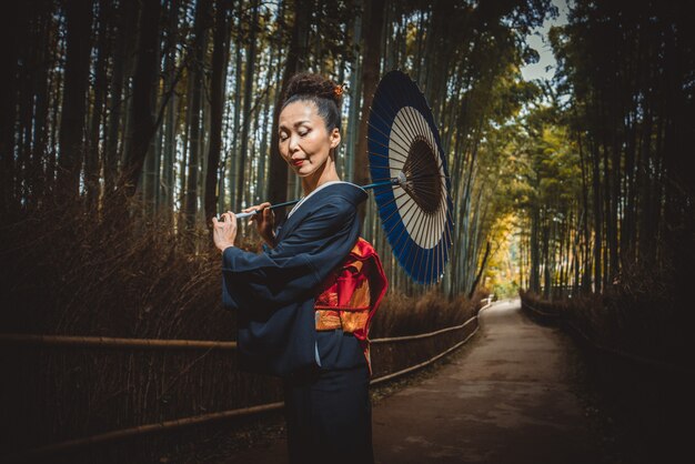 Mooie Japanse hogere vrouw die in het bamboebos loopt