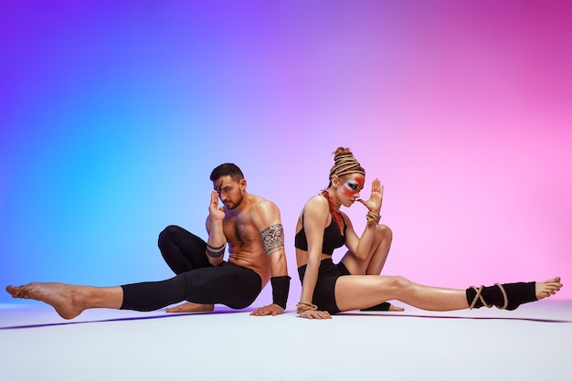 Mooie jonge acrobaten of gymnasten met kleurrijke schminken op roze blauwe achtergrond met kleurovergang Professioneel ballet paar dansen emotionele duet choreografische kunst uitvoeren dierlijk instinct