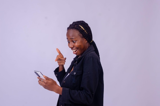 Mooie jonge Afrikaanse dame die opgewonden naar haar telefoonscherm wijst