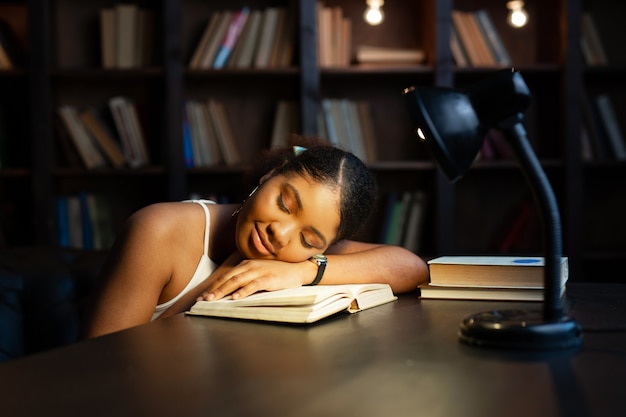 mooie jonge Afrikaanse vrouw slapen aan de tafel met boeken