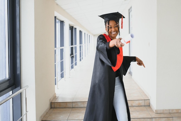 Mooie jonge Afro-Amerikaanse afgestudeerde met diploma