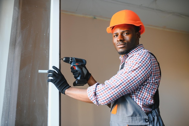 Mooie jonge Afro-Amerikaanse man die Bay Window installeert op de bouwplaats van een nieuw huis.