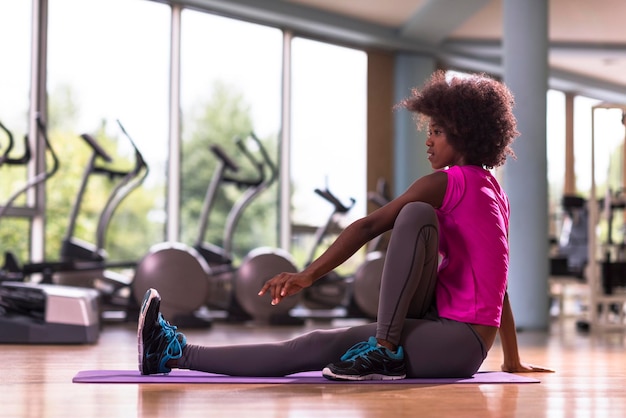 mooie jonge afro-amerikaanse vrouw oefent yoga uit in de sportschool