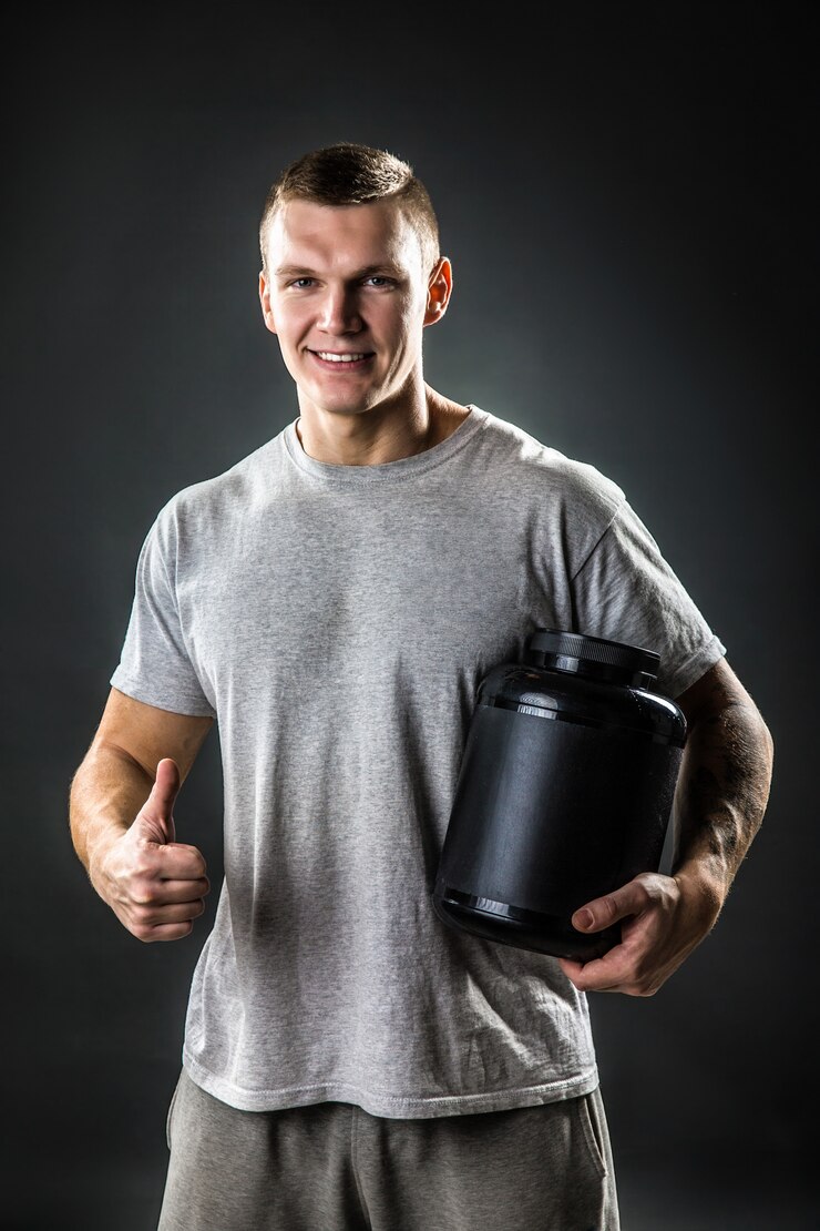 Mooie jonge atletische man met een potje sportvoeding