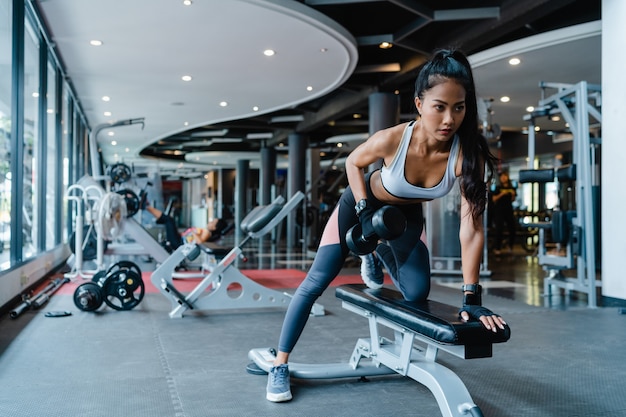 Mooie jonge Aziatische dame opheffing barbell vetverbranding training in fitness klasse.