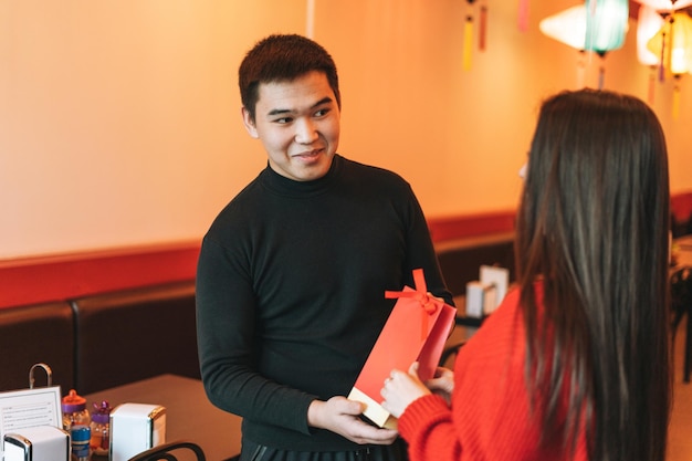 Mooie jonge Aziatische koppels geven cadeau in feestelijke Chinese restaurant kleurrijke papieren lantaarns