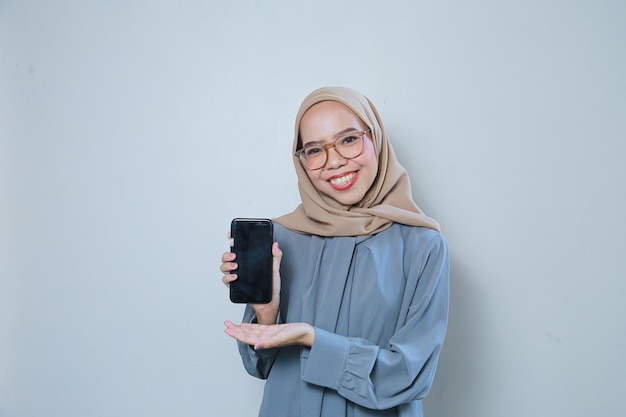 Mooie jonge Aziatische moslimzakenvrouw die een bril draagt terwijl ze de mobiele telefoon naar voren houdt