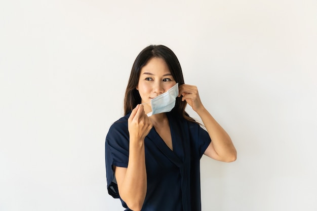 Mooie jonge aziatische vrouw die een medisch gezichtsmasker draagt voordat ze het huis verlaat. nieuw normaal, gezondheidszorgconcept. ruimte kopiëren