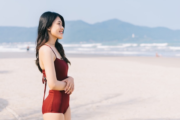 Mooie jonge Aziatische vrouw in badmode ontspannen op het strand tijdens zomervakantie