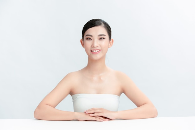 Mooie jonge Aziatische vrouw met schone frisse huid op witte muur,