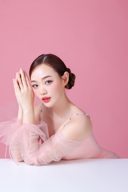 Foto mooie jonge aziatische vrouw model bun haar met natuurlijke make-up op het gezicht schone frisse huid op geïsoleerde roze achtergrond leuk meisje portret gezichtsbehandeling valentine concept