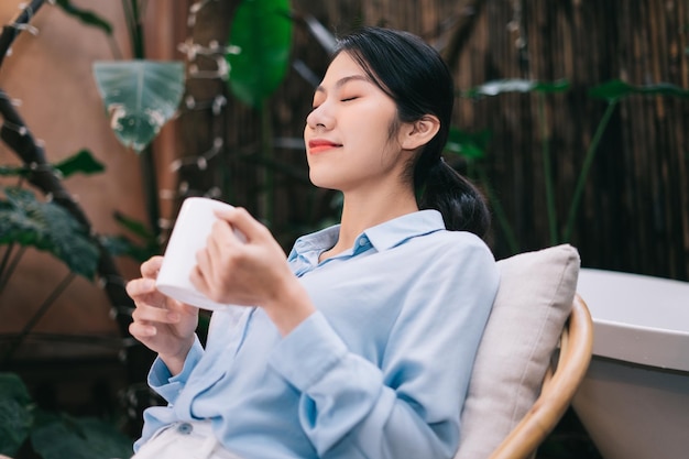 Mooie jonge Aziatische vrouw ontspannen in de tuin en het drinken van thee