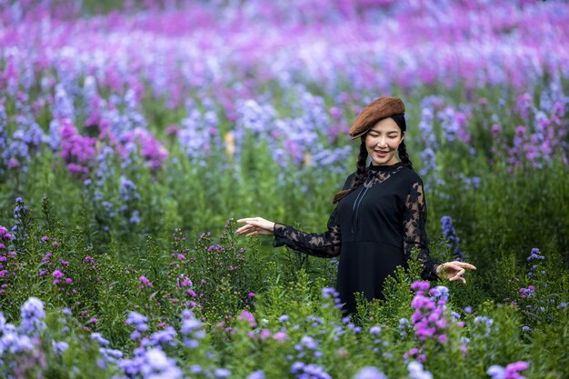 Mooie jonge Aziatische vrouw op zwarte jurk op violet of paars bloemenveld Aroma concept