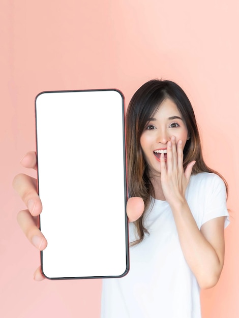 Mooie jonge Aziatische vrouw toont een grote smartphone met een leeg scherm wit scherm lege kopie ruimte voor reclame banner geïsoleerd op roze achtergrond Mock Up Image