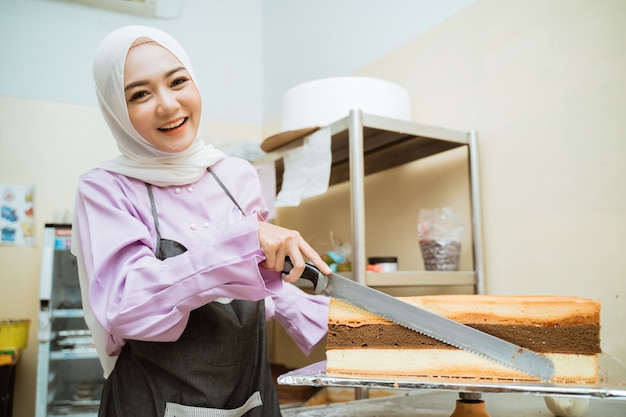 Mooie jonge bakker die cake maakt bij haar keuken. jonge aziatische moslim cakemaker