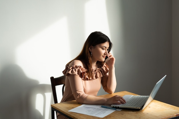 mooie jonge blanke vrouw aan de tafel met laptop