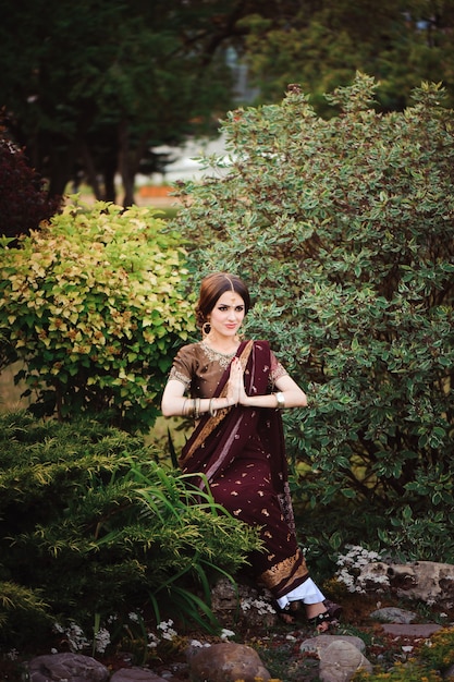 Mooie jonge blanke vrouw in traditionele Indiase kleding sari met bruids make-up en sieraden en henna tatoeage op handen.