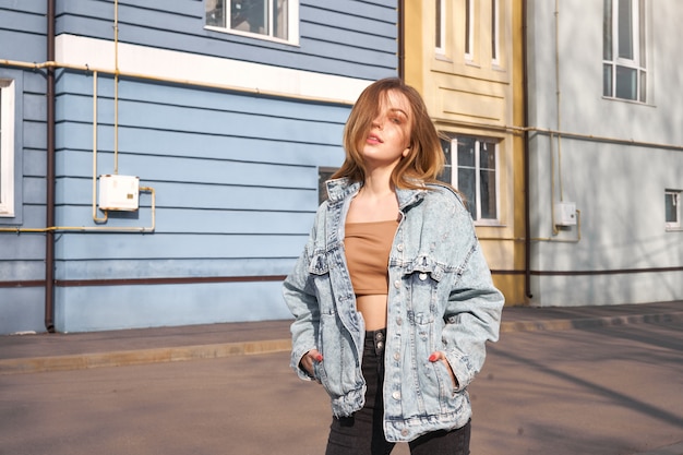 Foto mooie jonge blanke vrouw loopt straten van de stad warme zonnige zomerdag dragen denim jasje.