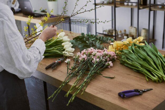 Foto mooie jonge bloemist maakt een boeket