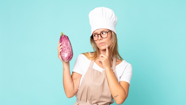 Mooie jonge blonde chef-kokvrouw met een aubergine