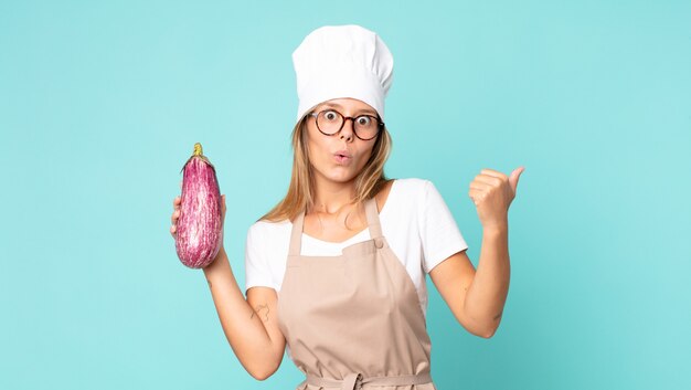 Mooie jonge blonde chef-kokvrouw met een aubergine