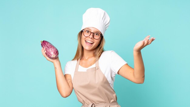 Mooie jonge blonde chef-kokvrouw met een aubergine