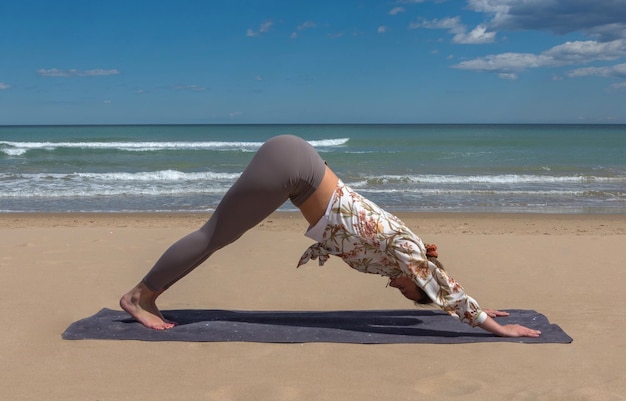 Mooie jonge blonde doet pilatus yoga op het strand