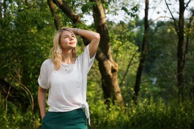 Mooie jonge blonde in het bos Het meisje geniet van de natuur