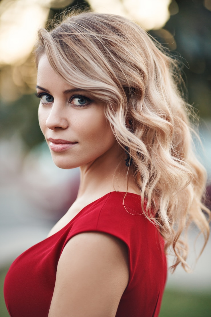 Foto mooie jonge blonde model in een rode jurk poseren