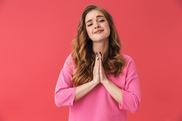 Mooie jonge blonde vrouw die geïsoleerd over roze muur staat en om iets vraagt