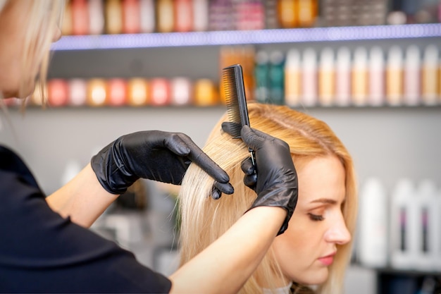 Mooie jonge blonde vrouw met lang steil blond haar dat een kapsel krijgt bij de kapsalon