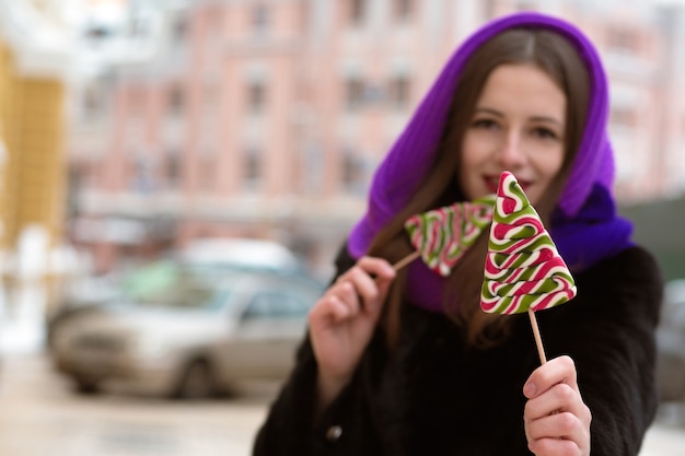 Mooie jonge brunette vrouw in paarse sjaal met kleurrijke kerstsnoepjes. Vervagingseffect