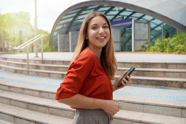Mooie jonge casual vrouw met telefoon klimt trappen om de metro te nemen in Brooklin station Sao Paulo, Brazilië