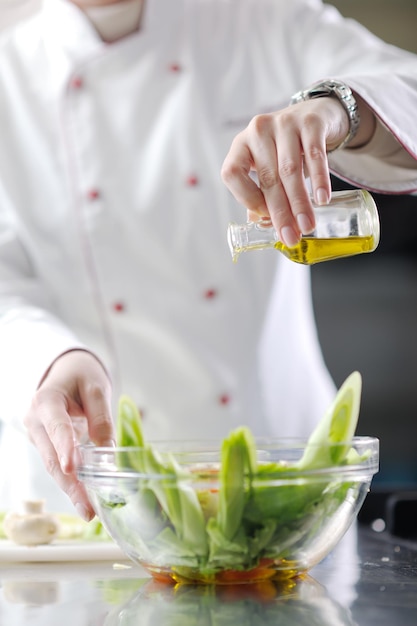 mooie jonge chef-kokvrouw bereidt en decoreert lekker eten in de keuken