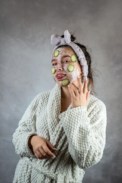 Mooie jonge dame met gezichtsmasker in procedure voor room en komkommercosmetica