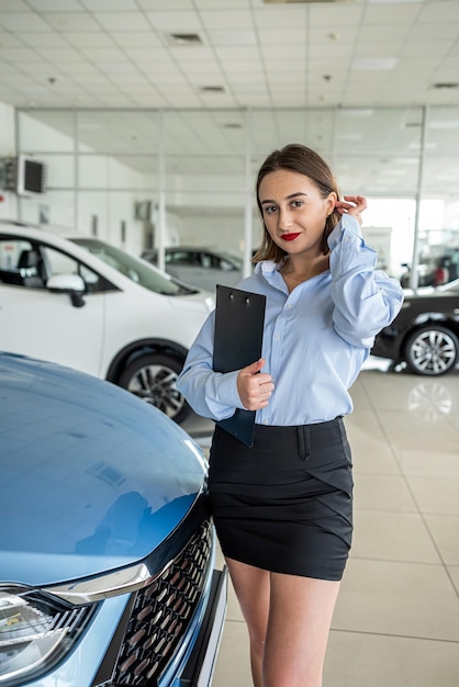 Mooie jonge dealer vrouw autoshowroom op de achtergrond