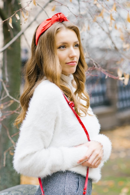 Mooie jonge Europese vrouw met een rode band in haar haar die in de herfst buiten loopt