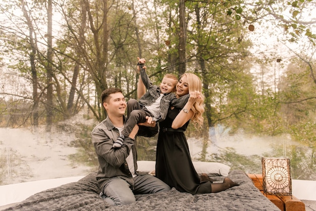 Mooie jonge familie man vrouw en zoon ontspannen in het bos in de natuur in een grote ronde tent met een bed en een fornuis om te koken, picknicken, kamperen