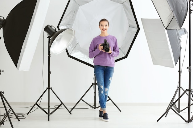 Mooie jonge fotograaf met camera in professionele studio