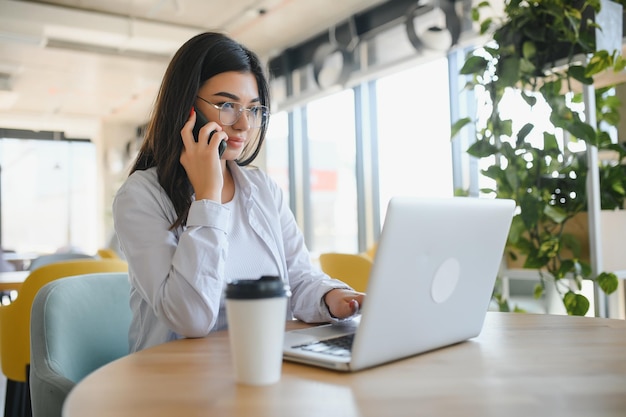 Mooie jonge freelancer vrouw met behulp van laptopcomputer zittend aan café tafel gelukkig lachend meisje online werken of studeren en leren tijdens het gebruik van notebook freelance werk mensen bedrijfsconcept