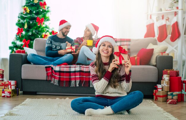 mooie jonge gelukkig lachende vrouw in een kerst trui en kerstmuts houdt een geschenkdoos