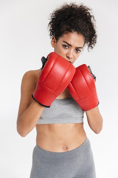 Mooie jonge geweldige sport fitness afrikaanse vrouw bokser poseren geïsoleerd over witte muur in handschoenen.